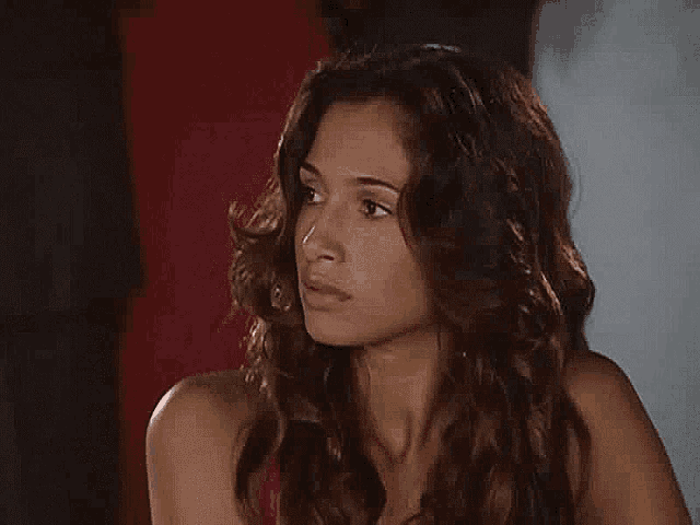 a woman with curly hair is looking at the camera with a serious look on her face .