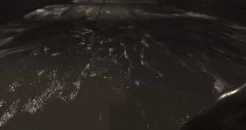 a black and white photo of a person standing in a pool of water .
