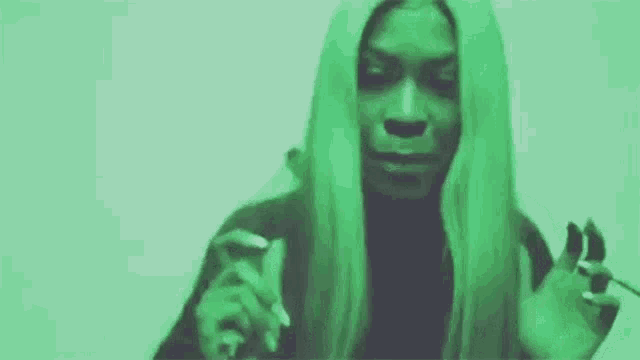 a woman with long blonde hair is making a funny face in a green background .