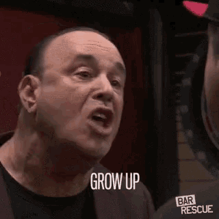 a man is making a funny face while talking to another man and saying `` grow up '' .