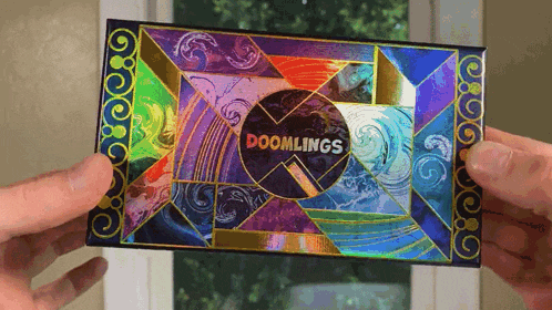 a person is holding a card that says doomlings in front of a window