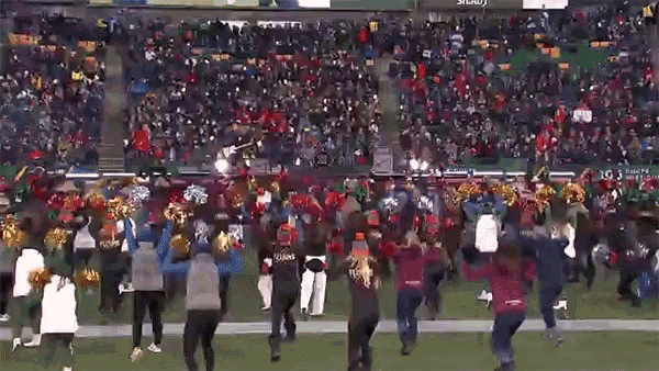 a group of cheerleaders are dancing on the field at a football game and one cheerleader is wearing a giants jersey