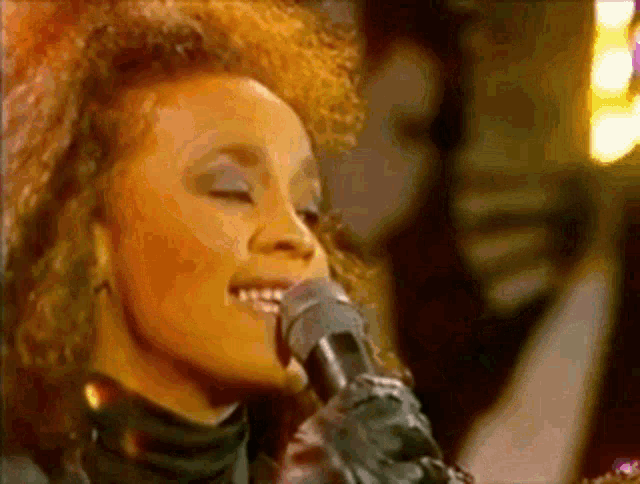 a woman is singing into a microphone with her eyes closed