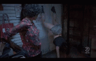 a woman is standing next to a man who is doing a handstand on the ground .