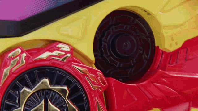 a close up of a yellow and red toy car with a black wheel