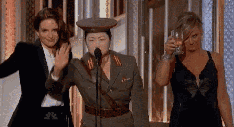 a woman in a military uniform is standing in front of a microphone while two women toast .