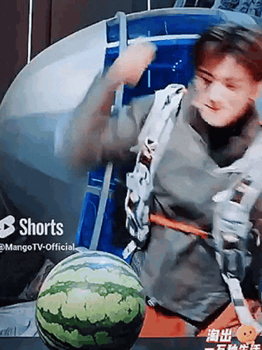 a man is holding a watermelon in front of a screen that says shorts on it