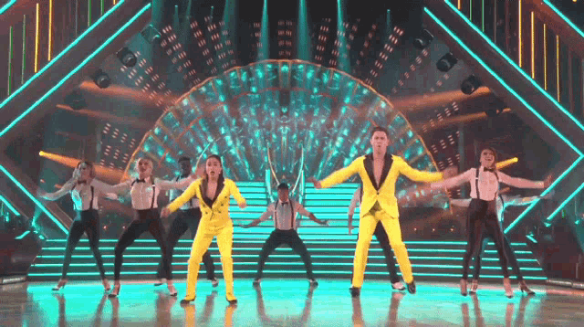 a group of dancers are performing on a stage with neon lights