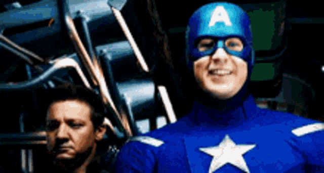 a man in a captain america costume stands next to another man