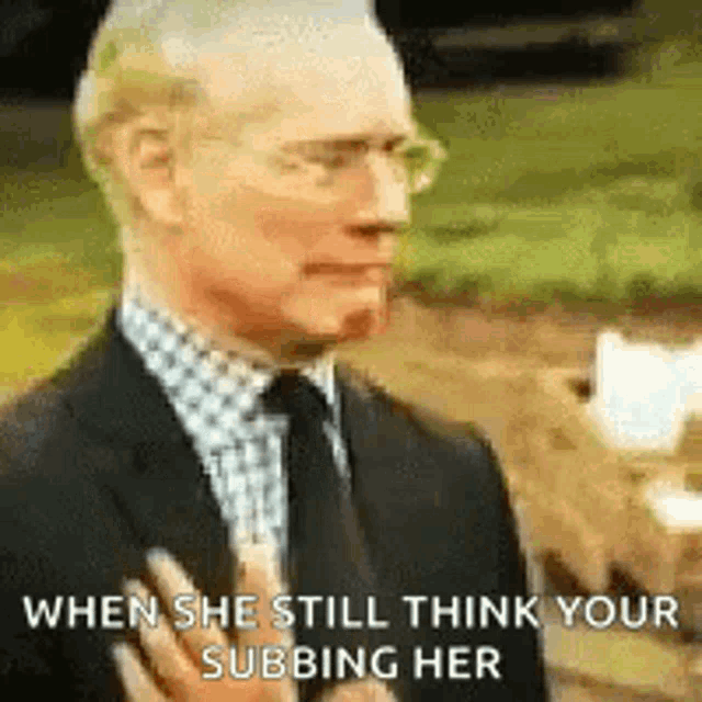 a man in a suit and tie is talking to a woman while holding his hand to his chest .