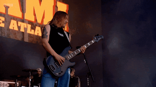 a man playing a guitar in front of a sign that says ' eatla '