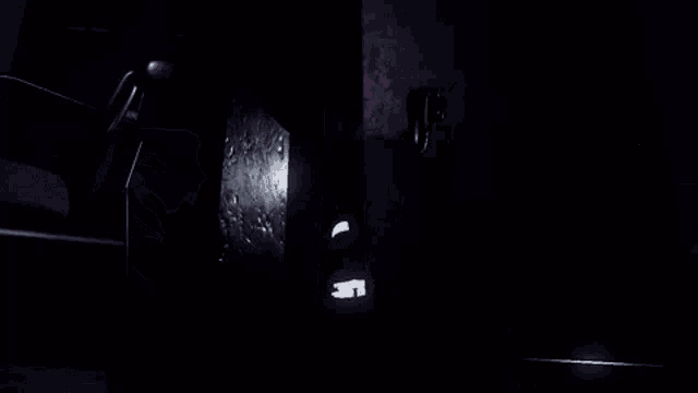 a person is standing in front of a mirror in a dark room with a light shining through it .