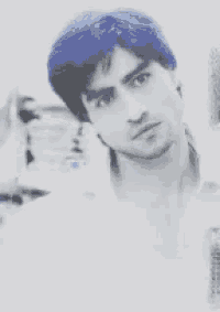 a man with blue hair is looking at the camera in a black and white photo