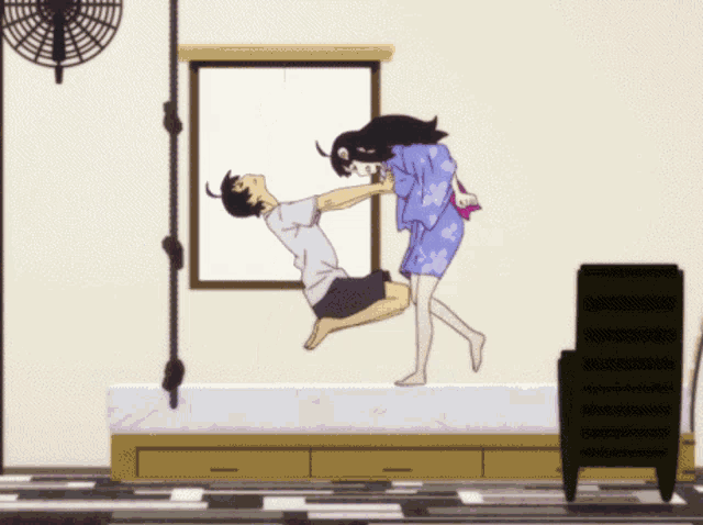 a man and a woman are kissing in a room with a fan hanging from the ceiling