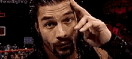 a man with a beard is making a funny face with his hand on his head .