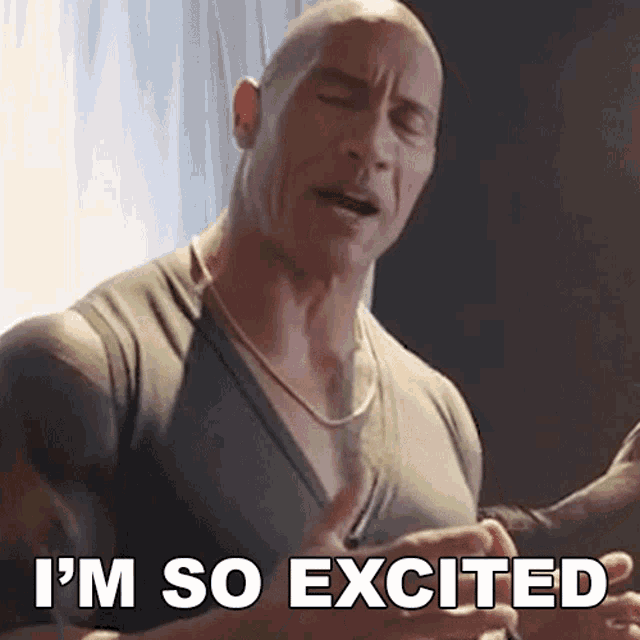 a bald man is saying i 'm so excited while wearing a chain around his neck .