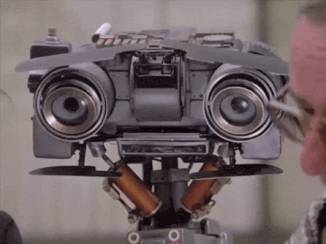 a man is looking at a robot that has the letter o on its face