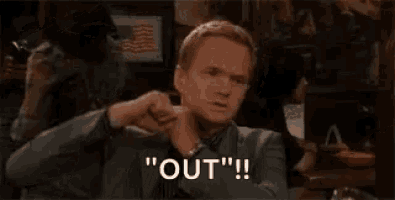 a man in a suit and tie is holding his fist up in the air and says `` out '' .