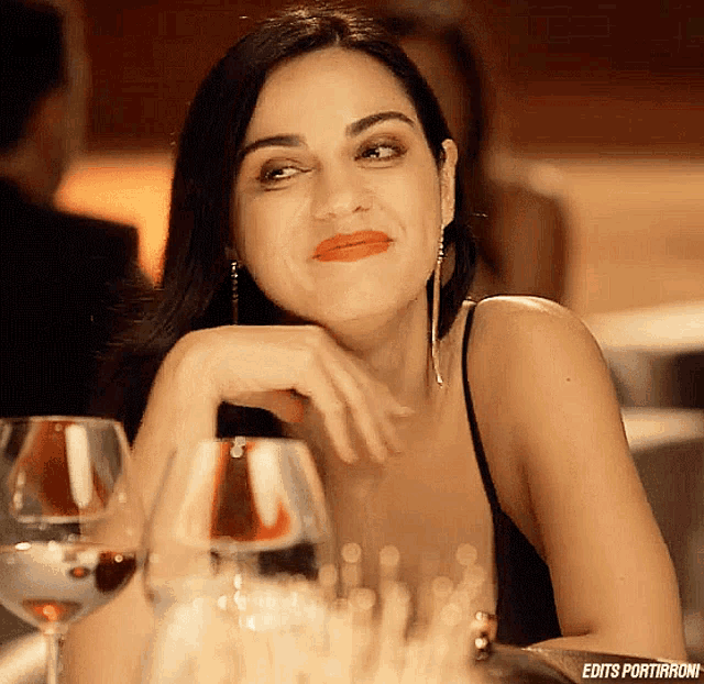 a woman in a black dress sits at a table with glasses of wine and a caption that says edits portirroni