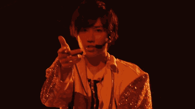 a man is singing into a microphone while wearing a white jacket