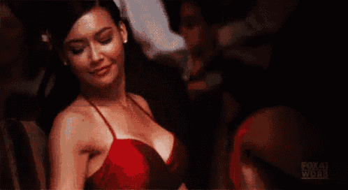 a woman in a red dress is sitting in a chair with her eyes closed and smiling .