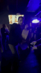 a woman is smiling in a dark room with purple lights behind her .