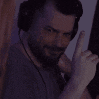 a man with a beard wearing headphones is giving a thumbs up sign .