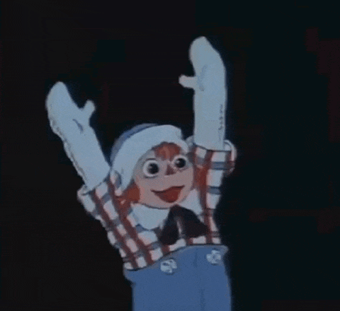 a cartoon character is holding up his arms in the air in a dark room .