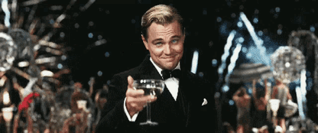 a man in a tuxedo holds up a glass of wine