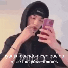 a man in a black hoodie is holding a cell phone .