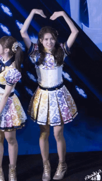 a girl in a colorful dress makes a heart with her hands