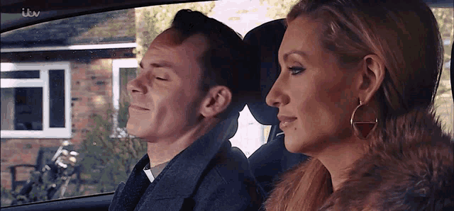 a man and a woman are sitting in a car with itv written on the screen