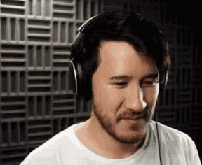 a man with a beard is wearing headphones and making a face .