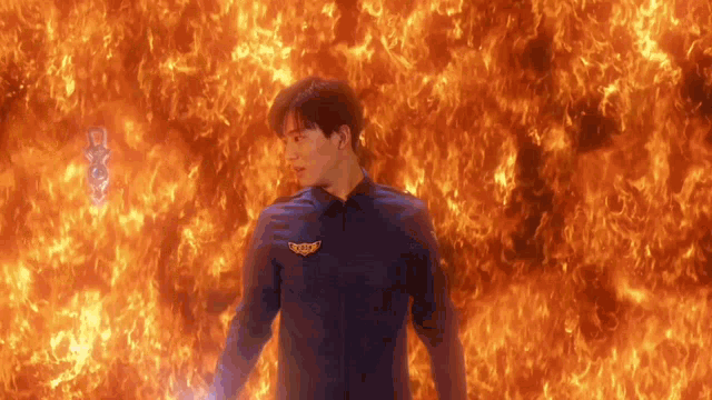a man is standing in front of a wall of fire