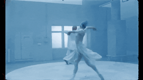 a couple of people are dancing in a room with a blue background