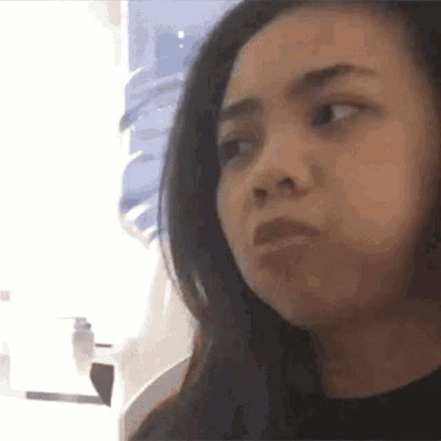 a woman with long hair is making a funny face while looking at the camera .