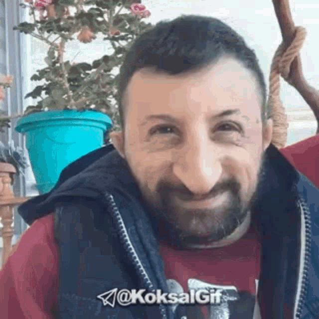 a man with a beard is making a funny face while wearing a vest and a red shirt .