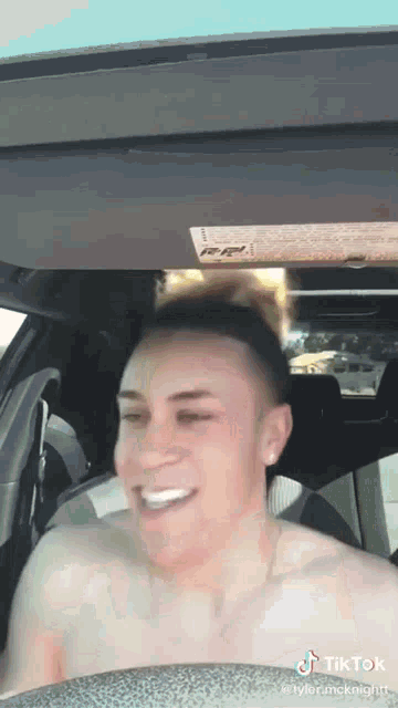 a man without a shirt is sitting in the back seat of a car .