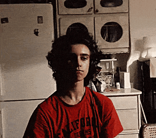 a young man wearing a red t-shirt that says warner bros.