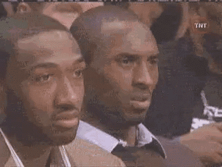 a couple of men sitting next to each other in a crowd .