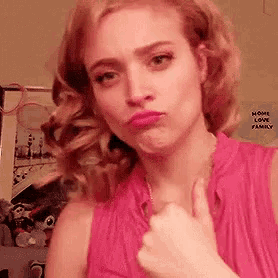 a woman in a pink shirt is giving a thumbs up sign .