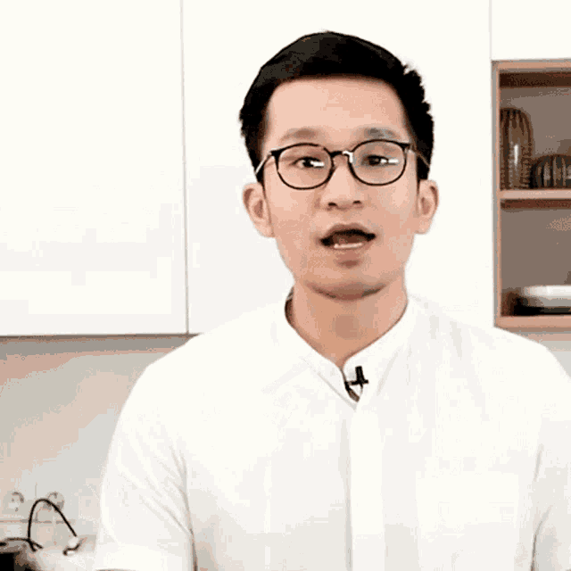 a young man wearing glasses and a white shirt is smiling