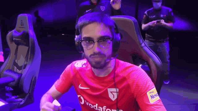 a man wearing glasses and a red vodafone shirt