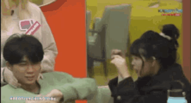 a man and a woman are sitting next to each other in a room . the man is wearing a green sweater .