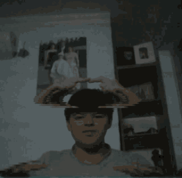 a blurry picture of a man 's face with a picture of a man and woman on the wall behind him