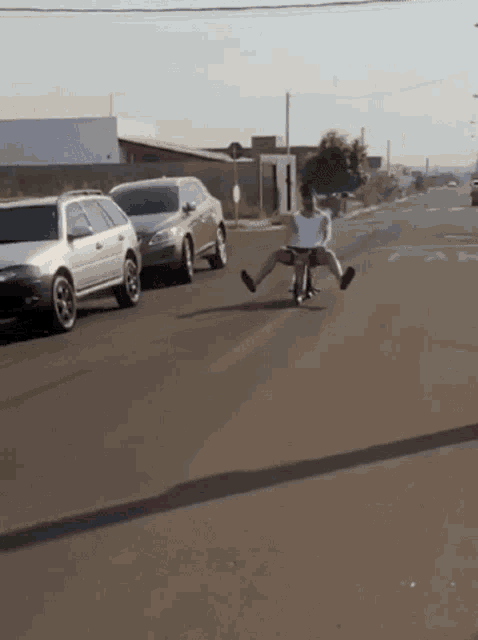 a man is riding a motorcycle down a street with cars parked behind him