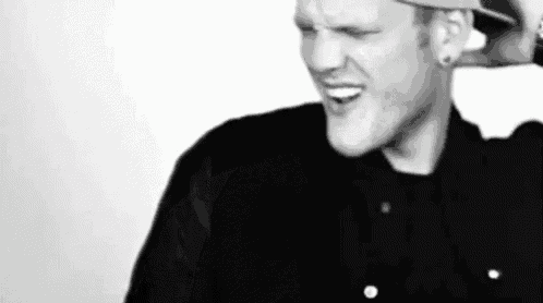 a black and white photo of a man wearing a hat and making a funny face .