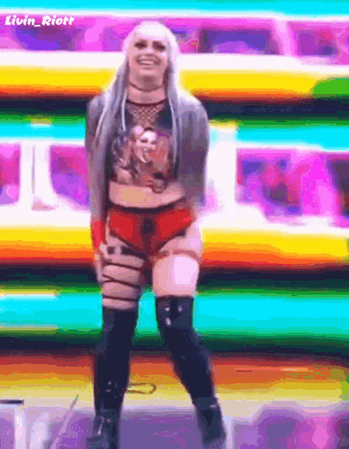 a woman is dancing in front of a colorful background and the name livin riott is on the bottom right