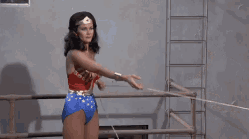 a woman in a wonder woman costume is standing in front of a man holding a rope .