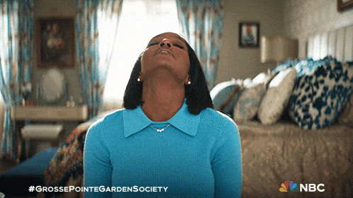 a woman in a blue sweater is sitting in a bedroom with the nbc logo on the bottom